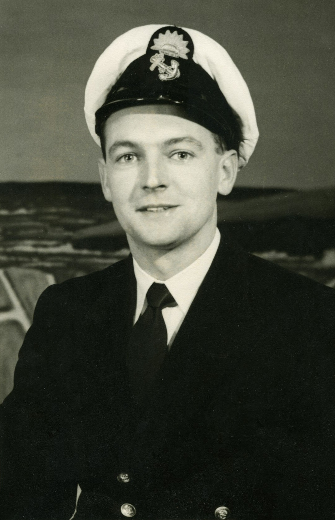 Portrait of a man in a navy suit smiling slightly
